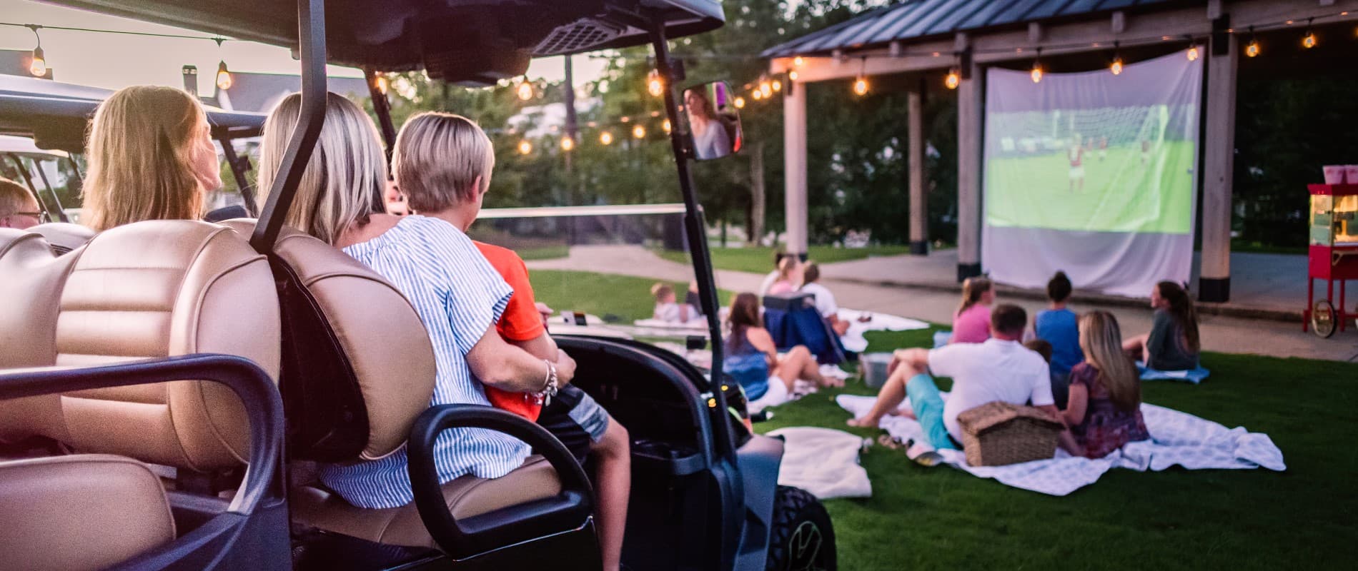 family in a golf cart watching a movie outside
